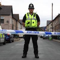A police officer stands guard at a cordon near a house in Newport, south Wales, on Wednesday as police continue their investigations into the Sept. 15 terrorist attack on a London subway train. | AFP-JIJI