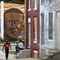 A mural depicts Freddie Gray in JUne 2016 near blighted row homes in Baltimore, at the intersection where Gray was arrested. The U.S. Department of Justice won\'t bring federal charges against six police officers involved in the arrest and death of Freddie Gray, a young black man whose death touched off weeks of protests and unrest in Baltimore. | AP