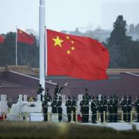 Chinese paramilitary policemen perform a flag-raising ceremony on Tiananmen Square in Beijing in this file photo. | AP