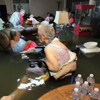 Residents of La Vita Bella nursing home in Dickinson, Texas, sit in floodwaters following the passage of Hurricane Harvey on Aug. 27. | AP