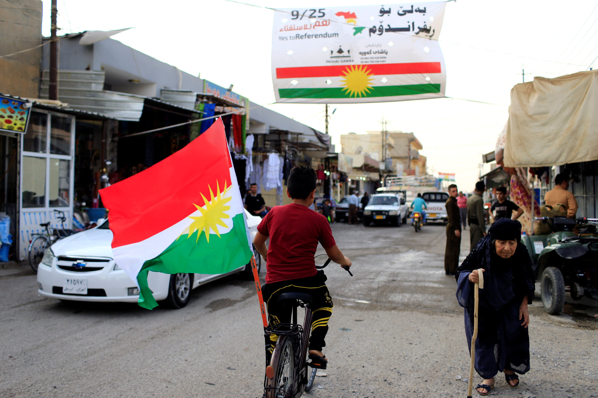 A boy rides a bicycle with the flag of Kurdistan in Tuz Khurmato, Iraq, Sunday. | REUTERS