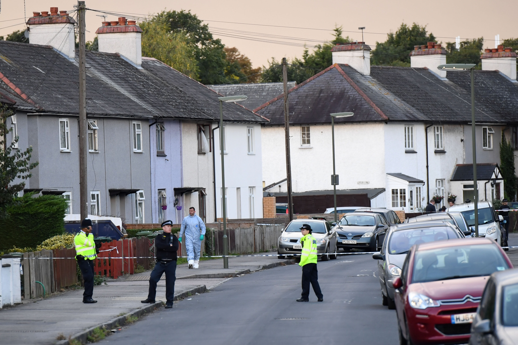 An investigator (center) leaves a house during a police raid on Saturday in Sunbury, Surrey, near London. | AFP-JIJI