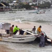 Fishermen take their boats out of the sea in anticipation of the arrival of Hurricane Max in Puerto Marquez, Guerrero state, Mexico, Thursday. | AFP-JIJI