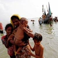 Rohingya refugees come ashore in Teknaf, Bangladesh, on Tuesday after crossing the Bay of Bengal from Myanmar. | REUTERS