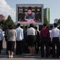 Spectators listen to a television news broadcast of a statement by North Korean leader Kim Jong Un outside the central railway station in Pyongyang on Friday. | AFP-JIJI