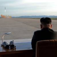 North Korean leader Kim Jong Un watches the launch of a Hwasong-12 intermediate-range ballistic missile in this photo released Saturday. | REUTERS