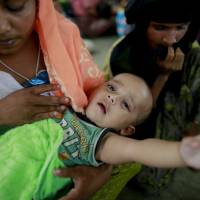 Rohingya woman Rahima sits with her 6-month-old childat a temporary shelter after being detained by Bangladeshi border guards while crossing the Naf River to enter Bangladesh at Shah Porir Deep, in Teknak, Bangladesh, Thursday. Three boats carrying ethnic Rohingya fleeing violence in Myanmar have capsized in Bangladesh and 26 bodies of women and children have been recovered, officials said Thursday. | AP