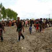 Members of the Border Guard Bangladesh (BGB) are seen on duty as they detain hundreds of Rohingya refugees in an open area after they crossed the border, in Teknaf, Bangladesh, Thursday. | REUTERS