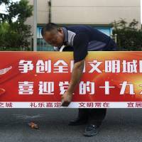 A worker installs a billboard Sunday that reads \'Creates a national civilized city, welcome the 19th Party Congress,\' near a residential area in Shanghai, China. The Chinese Communist Party meeting, which is held once every five years, will start on Oct. 18, marking the formal countdown to the gathering at which President Xi Jinping will begin his second five-year term as head of the ruling party. | AP