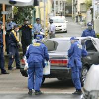 Police officers investigate the site where a former member of the Kobe Yamaguchi-gumi yakuza group was shot dead on Tuesday morning in the city. | KYODO