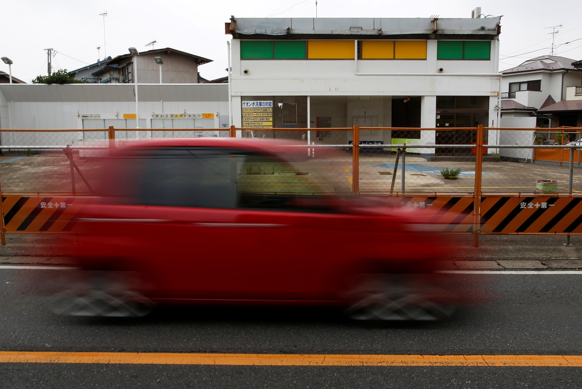 A car drives past a closed gas station in Chiba Prefecture on June 28. With waning demand for gasoline, the number of gas stations nationwide has roughly halved from a 1995 peak, leaving many mainly elderly people in remote areas a long way from the nearest pump to fill up. | REUTERS