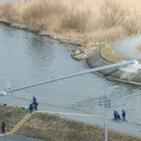 Police investigate the area where a 21-year-old woman was found murdered in the village of Miho, Ibaraki Prefecture in January 2004. Police arrested a Filipino man Saturday in connection with the case. | KYODO