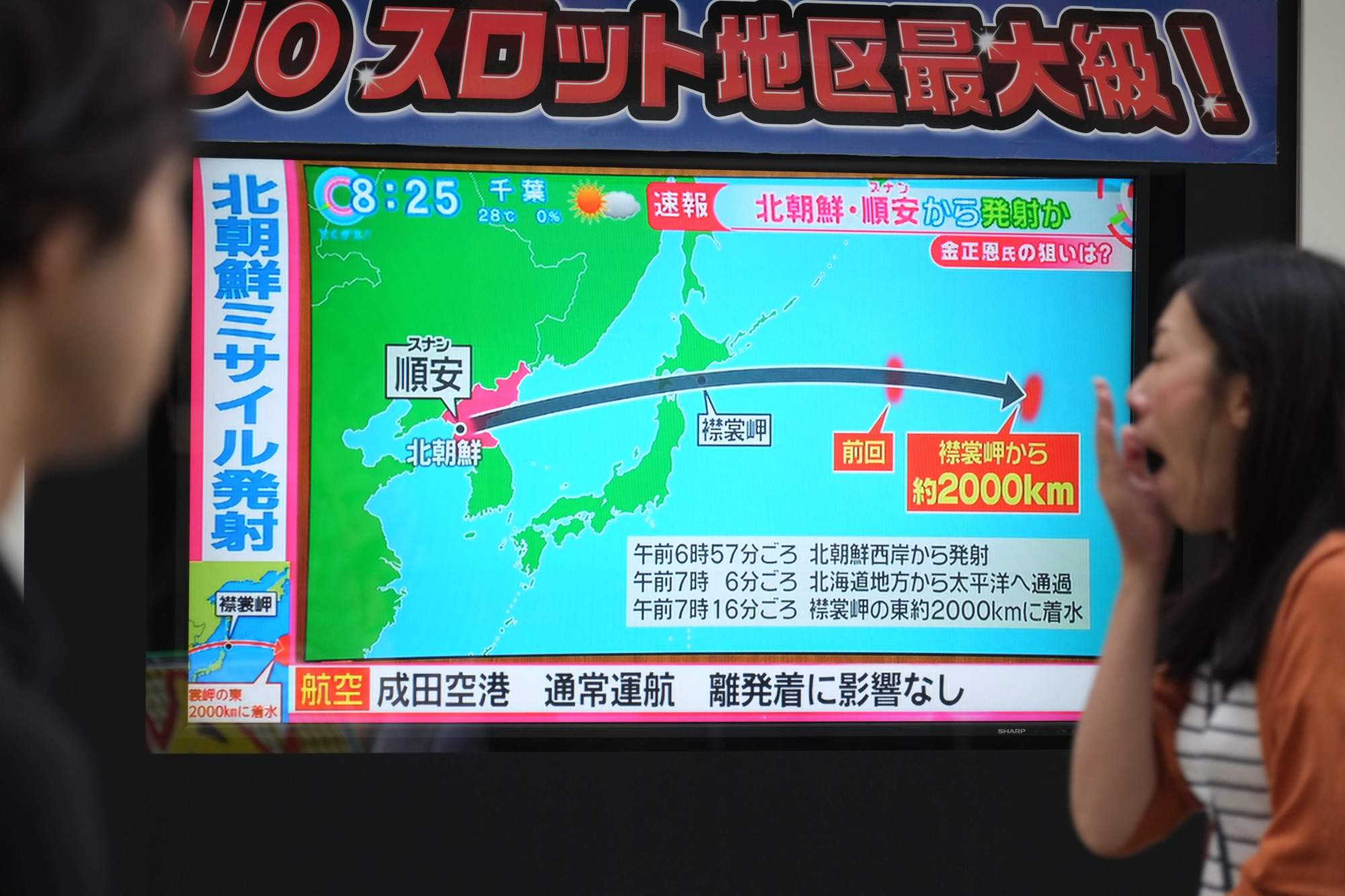 Pedestrians in Tokyo look at a TV screen broadcasting news of a North Korean missile that passed over Hokkaido early Friday morning. | AFP-JIJI