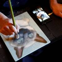 A painter paints a portrait of a pet cat at Pet Rainbow Festa, a pet funeral expo held in Tokyo on Monday. | REUTERS