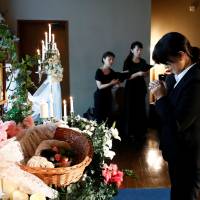 A staff prays in front of an altar for a pet dog during a demonstration of pet funeral services at the Pet Rainbow Festa, a pet funeral expo targeting an aging pet population, in Tokyo on Sept. 18. | REUTERS