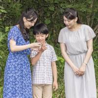 Prince Hisahito speaks with his sisters, Princesses Kako (left) and Mako, on Aug. 14 on the grounds of the Akasaka Detached Palace in Tokyo. | IMPERIAL HOUSEHOLD AGENCY / VIA KYODO