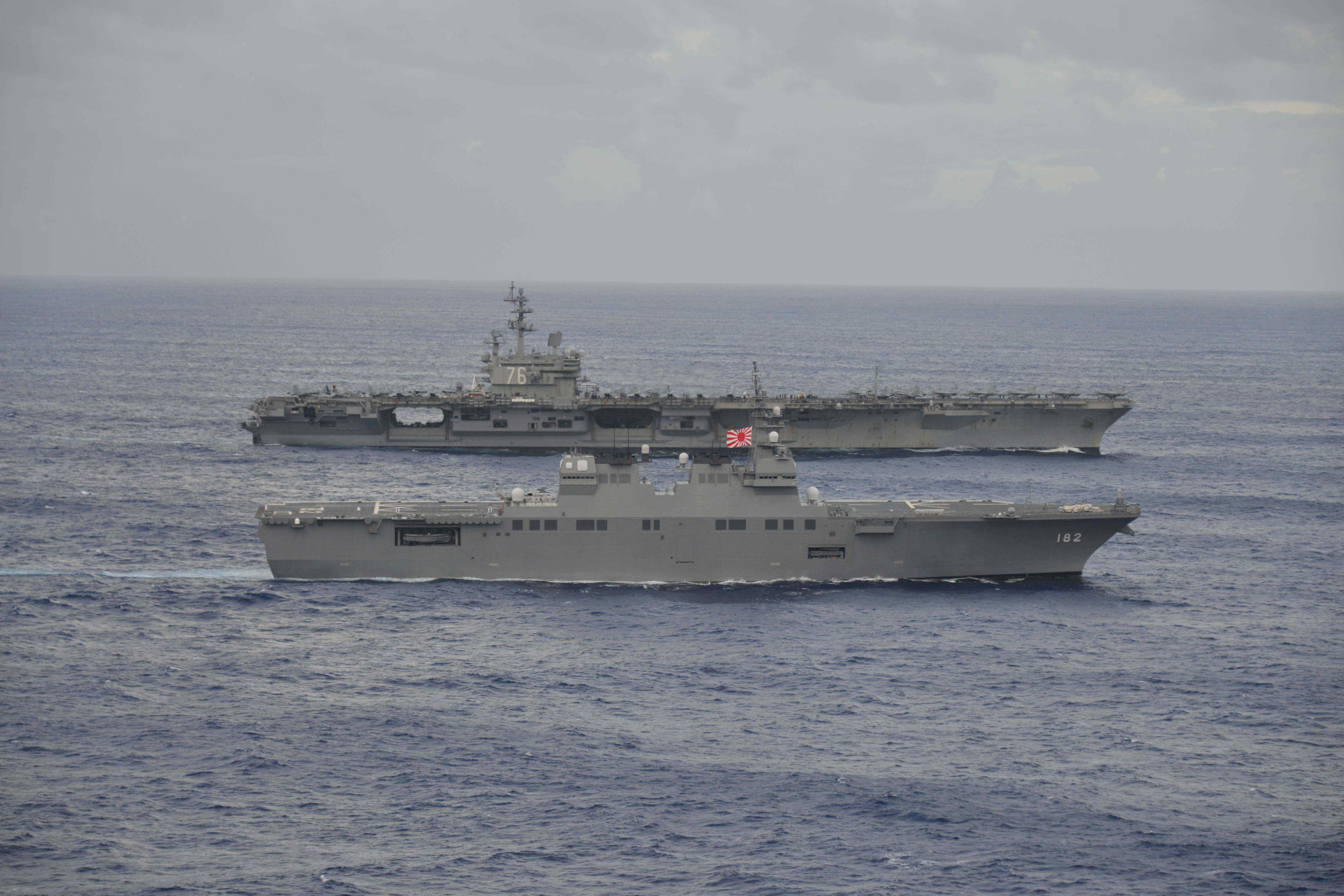 The aircraft carrier USS Ronald Reagan (rear) sails side-by-side with the Maritime Self-Defense Force's Hyuga-class helicopter destroyer Ise during joint military drills in the sea off Japan on Sept. 14. | MARITIME SELF-DEFENSE FORCE / VIA REUTERS