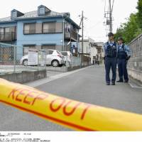 Police officers stand guard Monday by an apartment in Soka, Saitama, where a teenager was stabbed to death. The victim\'s girlfriend was also injured seriously in the attack, which was allegedly carried out by her former boyfriend. | KYODO