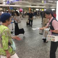 Railway company staff hand out packets of pocket tissues Tuesday at Yokohama station as part of a campaign asking the public to offer help to fellow commuters in need. | ALEX MARTIN