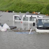 Vehicles are marooned when the Ono River in Oita Prefecture overflowed its banks on Sunday after Typhoon Talim moved across Kyushu and on to Shikoku. | KYODO