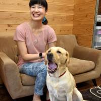 Kanako Suzuki sits with her guide dog, Ariel, in August. | SATOKO KAWASAKI
