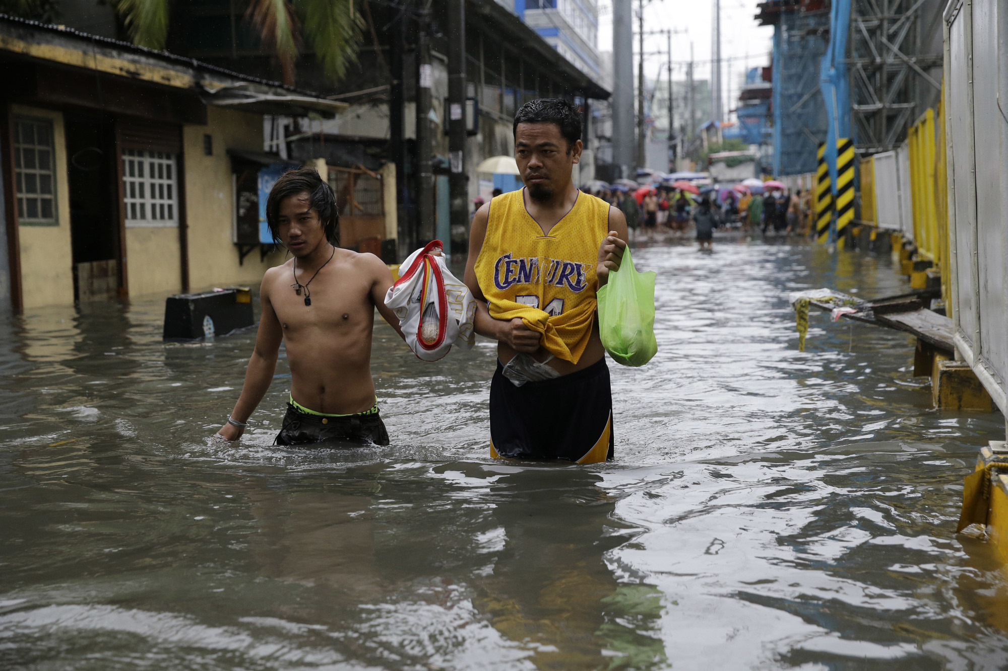 Residents wade though a flooded street in Manila on Tuesday after heavy rains swamped low-lying areas. | AP