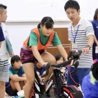 An applicant for the Japan Rising Star Project rides a training bike during an Aug. 26 event at Nippon Sport Science University. | KAZ NAGATSUKA