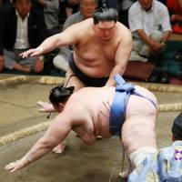 Goeido (rear) throws Aoiyama to the ground at the Autumn Grand Sumo Tournament on Monday. | KYODO