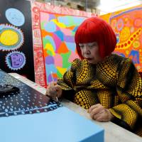Avant-garde artist Yayoi Kusama, 88, speaks to the media at her studio in Tokyo on Tuesday. Kusama, whose exhibitions have been among the hottest tickets in the art world, is now opening a museum in downtown Tokyo dedicated to her paintings and sculptures. | REUTERS