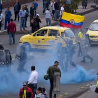 Police officers try to disperse a protest staged by taxi drivers over the private hire company Uber in Bogota Monday. | AFP-JIJI