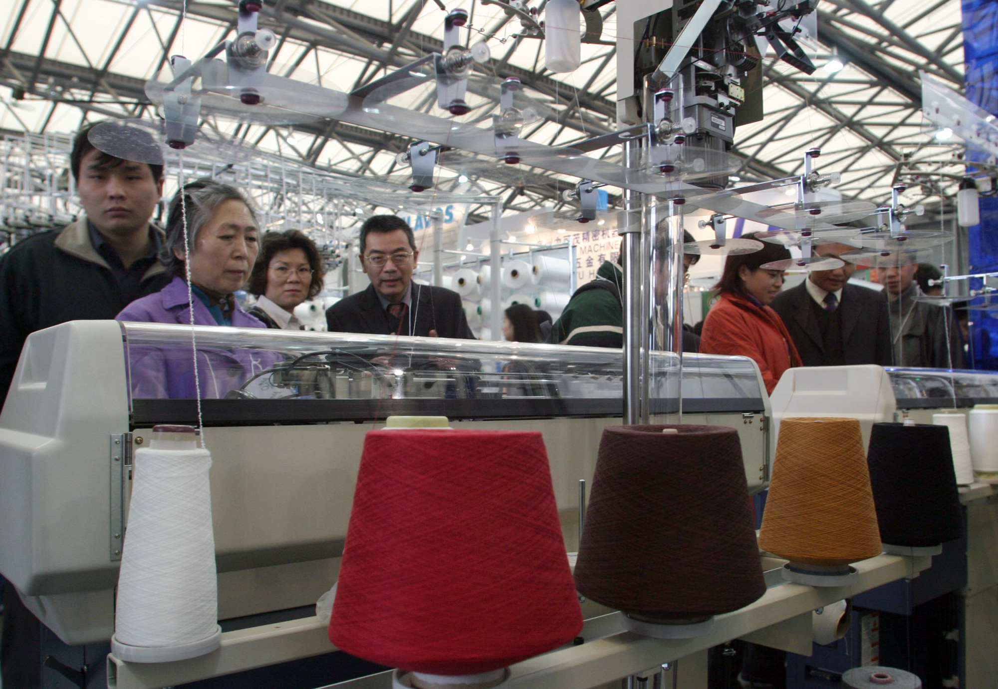 Chinese visitors look at a knitting machine at 'Shanghaitex 2003,' the 10th International Exhibition on Textile Industry, in Shanghai, China in 2003. | BLOOMBERG NEWS
