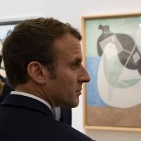 French President Emmanuel Macron stands by Pablo Picasso\'s 1932 painting \"Woman lying in the sun\" during the opening of the \"Picasso 1932: Erotic Year\" exhibition at the Picasso museum in Paris, on Sunday. | IAN LANGSDON / POOL / VIA AFP-JIJI