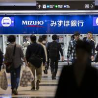 Struggling amid low interest rates, Mizuho Financial Group Inc. is thinking of slashing its entire labor force by a third over a 10-year period. | BLOOMBERG