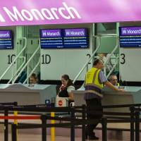 Staff sit at the check-in desks for Monarch Airlines, in the departures area of Birmingham Airport in Birmingham, central England, Monday. British short-haul carrier Monarch Airlines ceased trading suddenly Monday following a financial collapse, the biggest failure of its kind in Britain, prompting the government into emergency action in returning home 110,000 stranded passengers. | AFP-JIJI