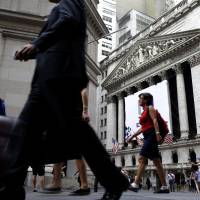 People pass the New York Stock Exchange in 2015. Congress is looking for ways to raise revenue, and one of the methods reportedly under consideration is to limit how much pretax money workers can contribute to their 401(k) and similar accounts. If it were to happen, the move would strike at a way that tens of millions of Americans use to save for retirement. | AP
