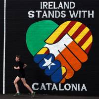 A runner passes a new mural on the Nationalist Falls Road in Belfast, Northern Ireland, on Sunday. | REUTERS