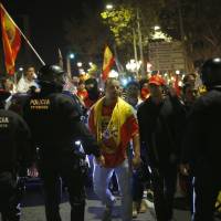 Catalan police officers stand to prevent Spanish demonstrators from moving forward during a march against the unilateral declaration of independence approved earlier by the Catalan parliament in downtown Barcelona on Friday. | AP