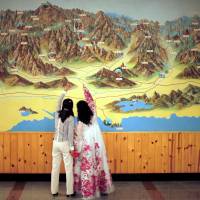 People point to a map on a wall at the Mount Kumgang resort in Kumgang, North Korea, in September 2011. | REUTERS