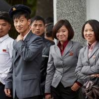 College students from the Wonsan Agricultural University in Wonsan, North Korea, shelter from the rain under a university building in October 2016. | CHRISTIAN PETERSON-CLAUSEN / VIA REUTERS