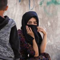 Displaced Iraqi Kurdish people fleeing violence in the northern Kirkuk province sit an unfinished housing project where they are taking shelter in Irbil, the capital of the autonomous Kurdish region of northern Iraq, on Thursday. | AFP-JIJI