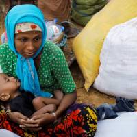 Rohingya refugees, who crossed the border from Myanmar two days before, rest as they wait to receive humanitarian aid at the Kutupalong refugees camp near Cox\'s Bazar, Bangladesh, Thursday. | REUTERS