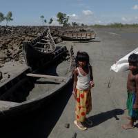 Children collect wood from remnants of some 20 boats that ferried Rohingya refugees fleeing violence in Myanmar that were destroyed by Bangladeshi authorities the night before, at Shah Porir Dwip near Cox\'s Bazar, Bangladesh, Wednesday. | REUTERS