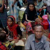 Rohingya refugees who arrived by boat fleeing violence in Myanmar the night before, wait to receive aid at a relief center at Teknaf near Cox\'s Bazar, Bangladesh, Wednesday. | REUTERS