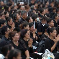 Mourners react as the Royal Urn of late King Bhumibol Adulyadej is carried by the Great Victory Chariot during a royal cremation procession at the Grand Palace in Bangkok Thursday. | REUTERS