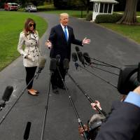 U.S. President Donald Trump speaks to reporters upon his departure from the White House on Friday. Beside him is first lady Melania Trump. | REUTERS