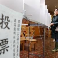 A ballot sign dangles as a prospective voter navigates a polling station in Tokyo during the Lower House election on Sunday. | REUTERS
