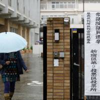 A woman holding an umbrella leaves a polling station in Tokyo during the general election on Sunday. | BLOOMBERG