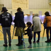 Voters fill out ballots during the general election at a polling station in Tokyo\'s Minato Ward on Sunday. | SATOKO KAWASAKI