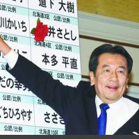 Constitutional Democratic Party of Japan leader Yukio Edano places a paper flower on the name of a winning candidate in the Lower House election in Tokyo on Sunday.  | SATOKO KAWASAKI