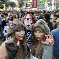 Revelers in Halloween attire pose near Shibuya\'s scramble crossing on Oct. 29 last year. | YOSHIKAI MIURA